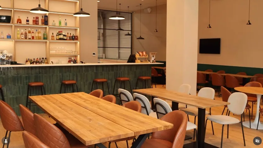 La salle et son bar en carrelage vert, chaises en cuir cognac